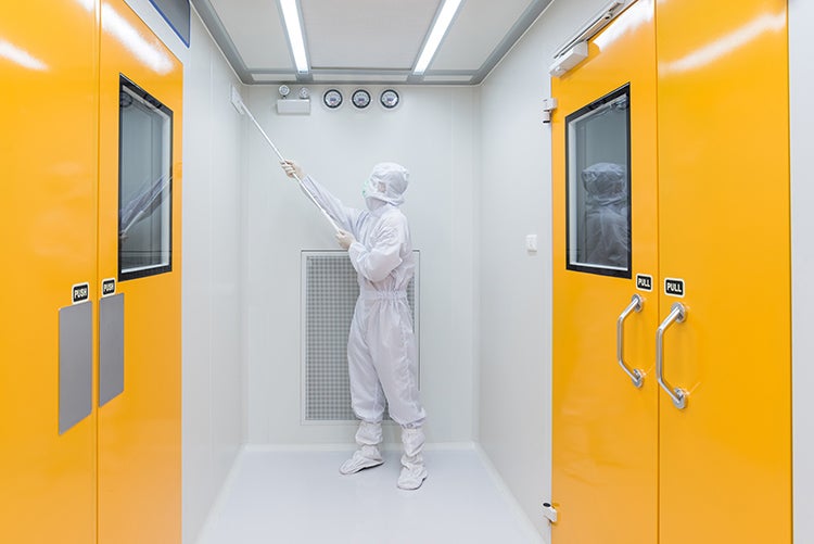 person in PPE cleaning a cleanroom