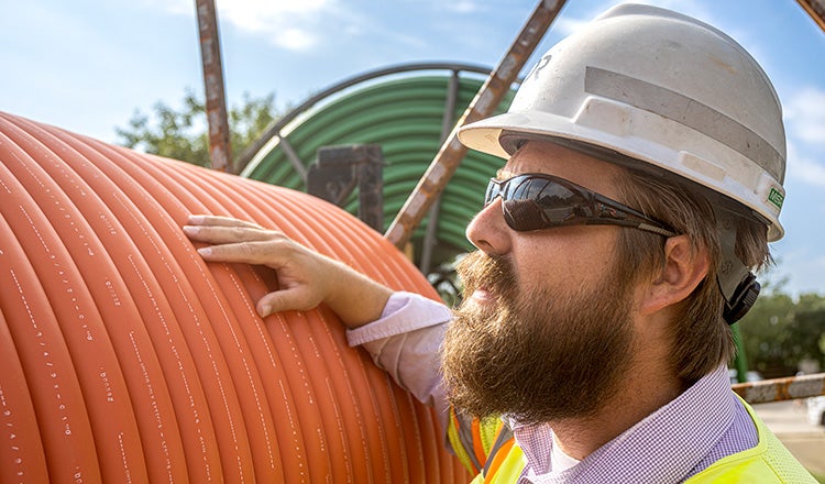 HDR employee standing next to reel of conduit