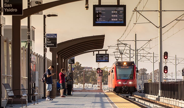 people waiting at transit station for approaching train