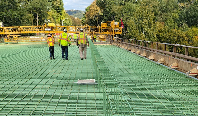 construction workers walking across rebar used in Fern Hollow bridge deck