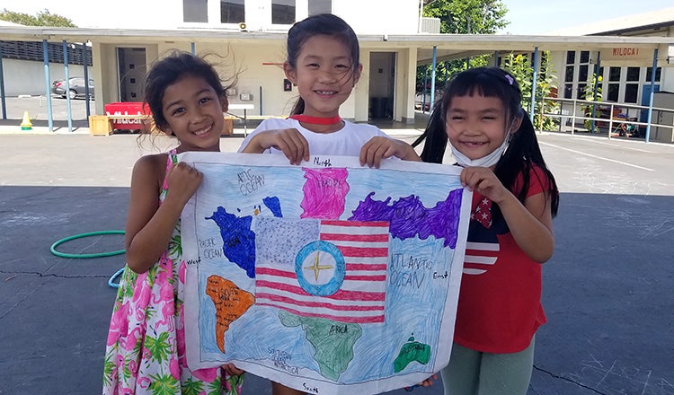 Girls pose with a world map