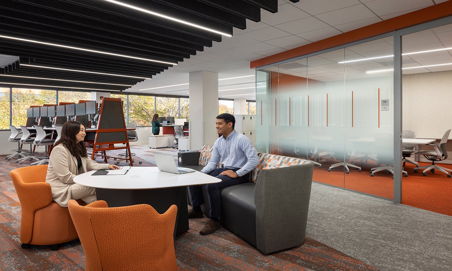 Office space interior with workers sat at desk.