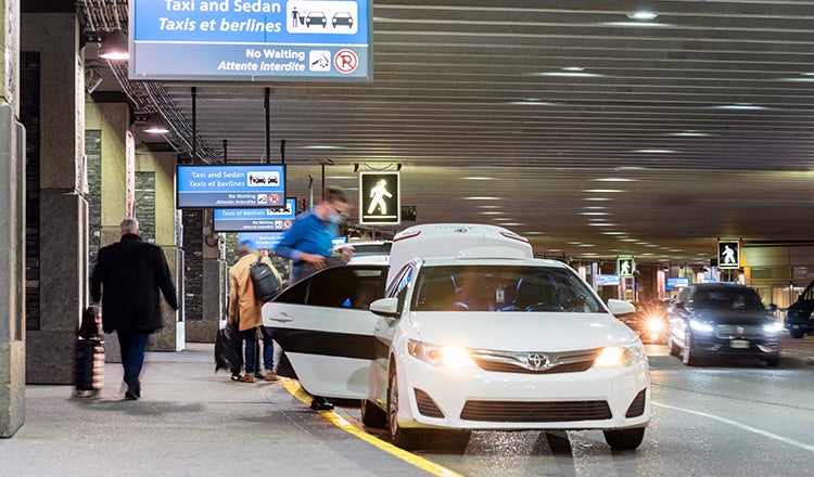 man getting into car at airport curb