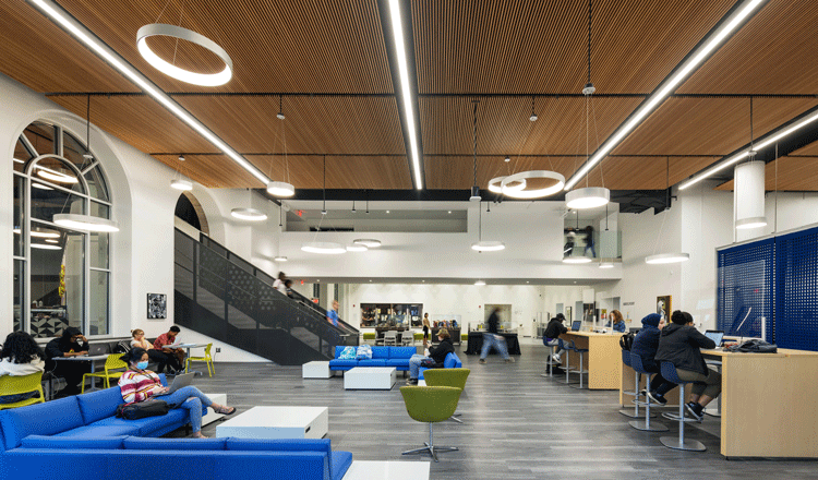 A group of diverse students sitting in and walking through the reading room at the Community College of Philadelphia Library and Learning Commons