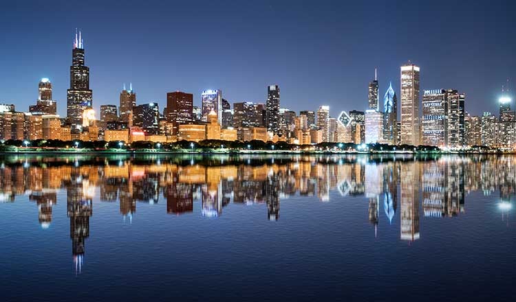 Nighttime skyline of Chicago. Skyscrapers show in the background. River shown in foreground., 