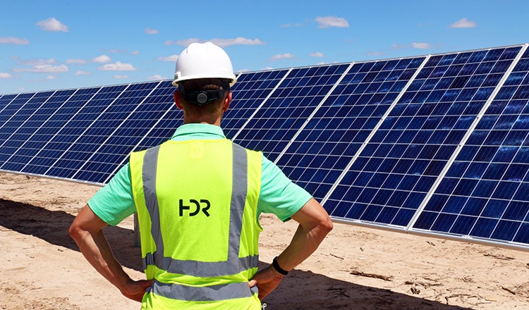 solar panels, with man in HDR safety vest standing in front