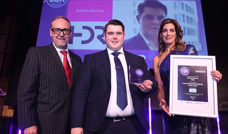 Three people on stage with an award presented.