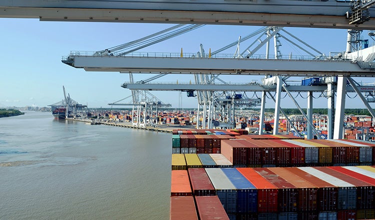 container ship at port with cranes in foreground