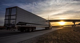 truck driving toward sunset on highway