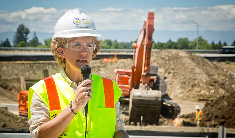 Julie Labonte talking into a mic in front of a construction site