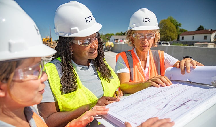 three women looking at construction plans 