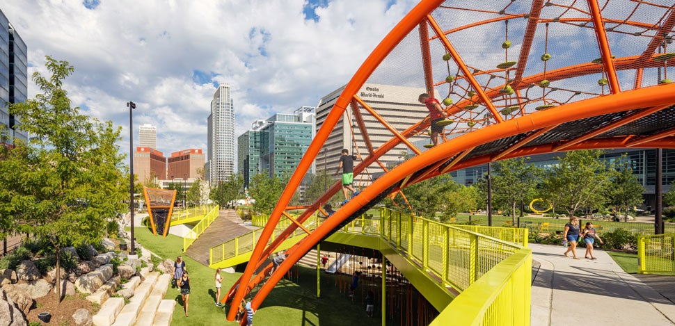 A play structure in a park that resembles a bridge, with kids playing on it