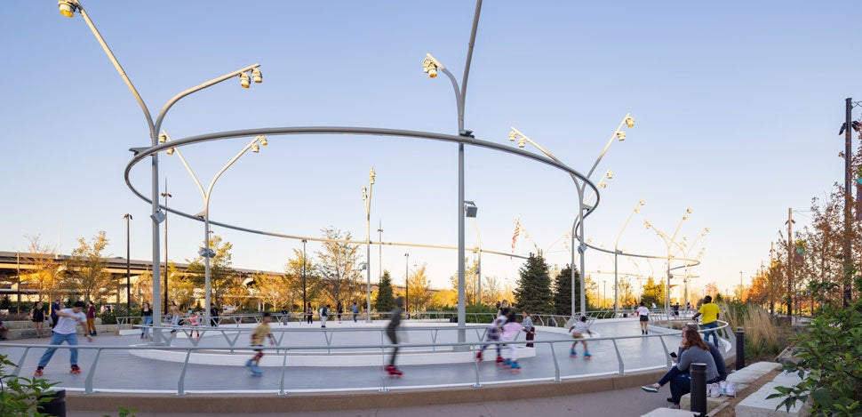 People rollerblading in an outside roller rink in a park