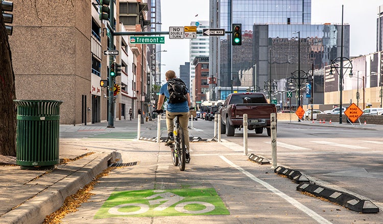 man riding away from camera on bicycle in bike lane