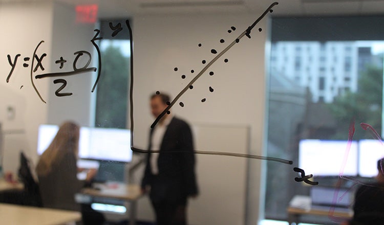 formula and graph on glass with professionals in background
