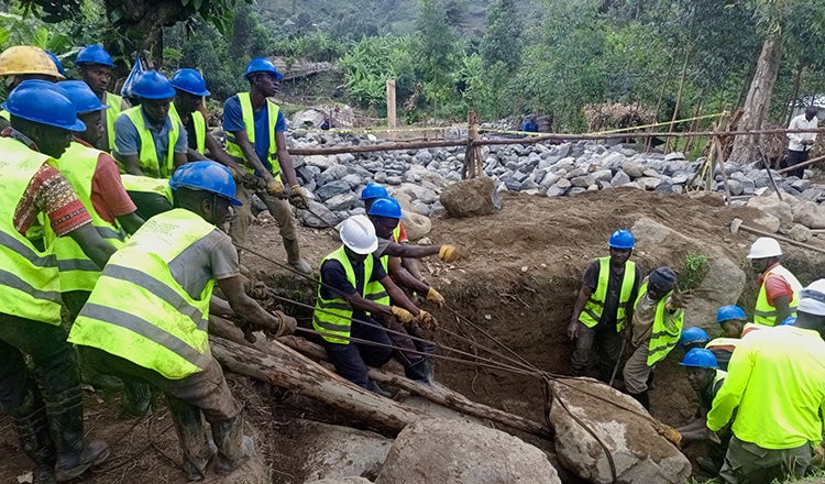 Workers removing boulder during bridge construction