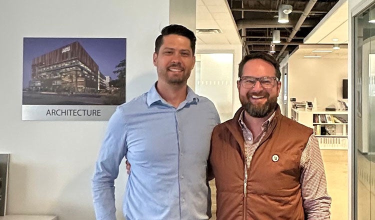 Tim Baron and Andrew Elmer posing in office hallway with smiles