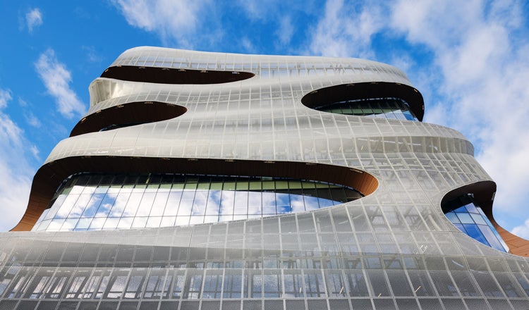Large metal and glass building with design-forward envelope, blue sky in the background