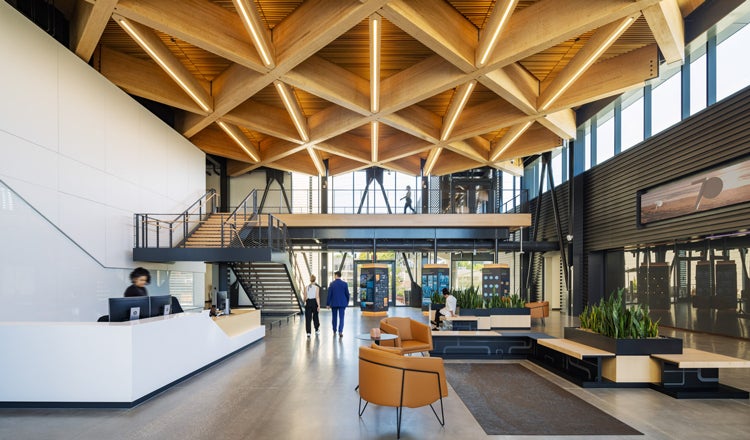 Modern office lobby with a mass timber geometric ceiling, people walking around