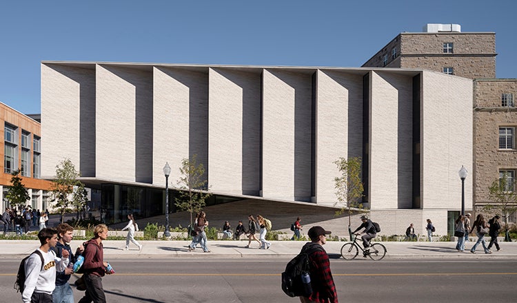 Students walking past a campus building with a staggered facade