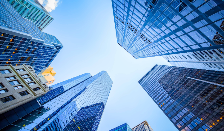 Looking up at skyscrapers in Manhattan from street level during the daytime.