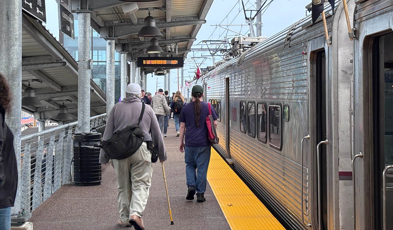 people walking on platform next to commuter train