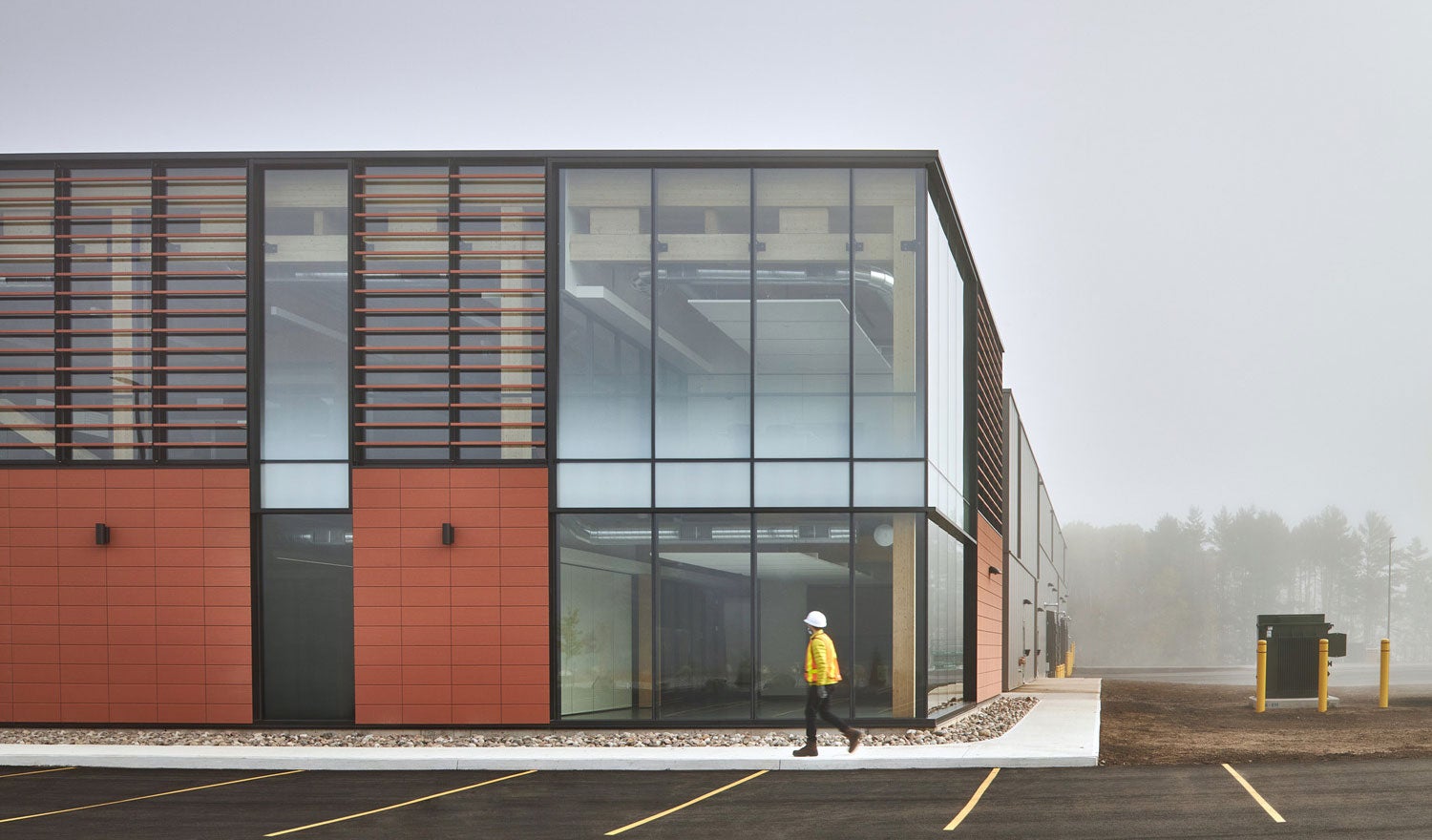 Two-story building with frosted windows and facade, and someone walking past in construction apparel