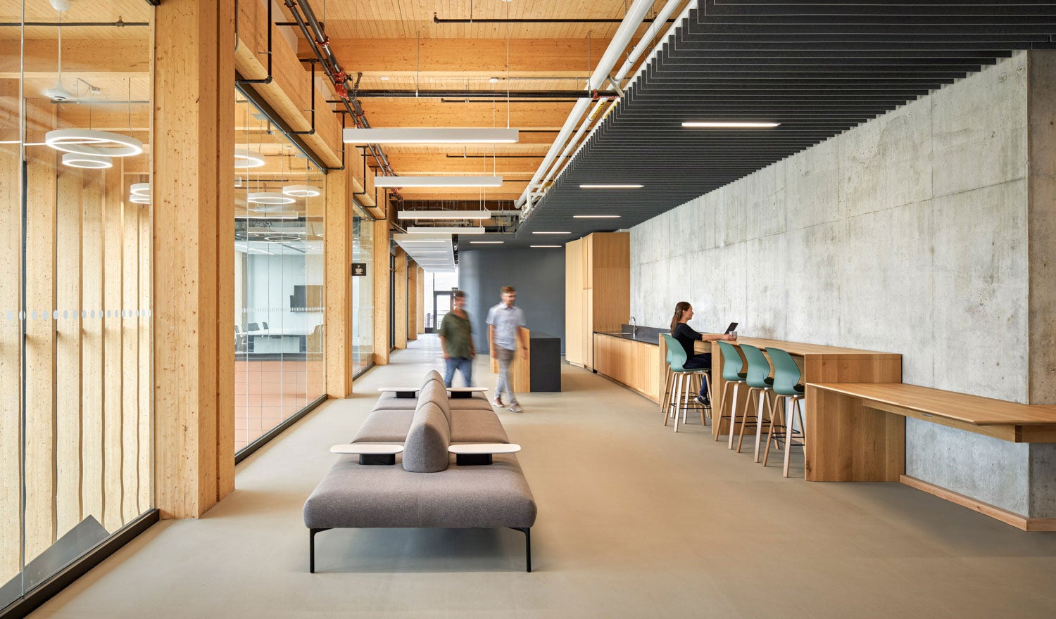 Employees in a modern office building with wood interiors, walking through and working