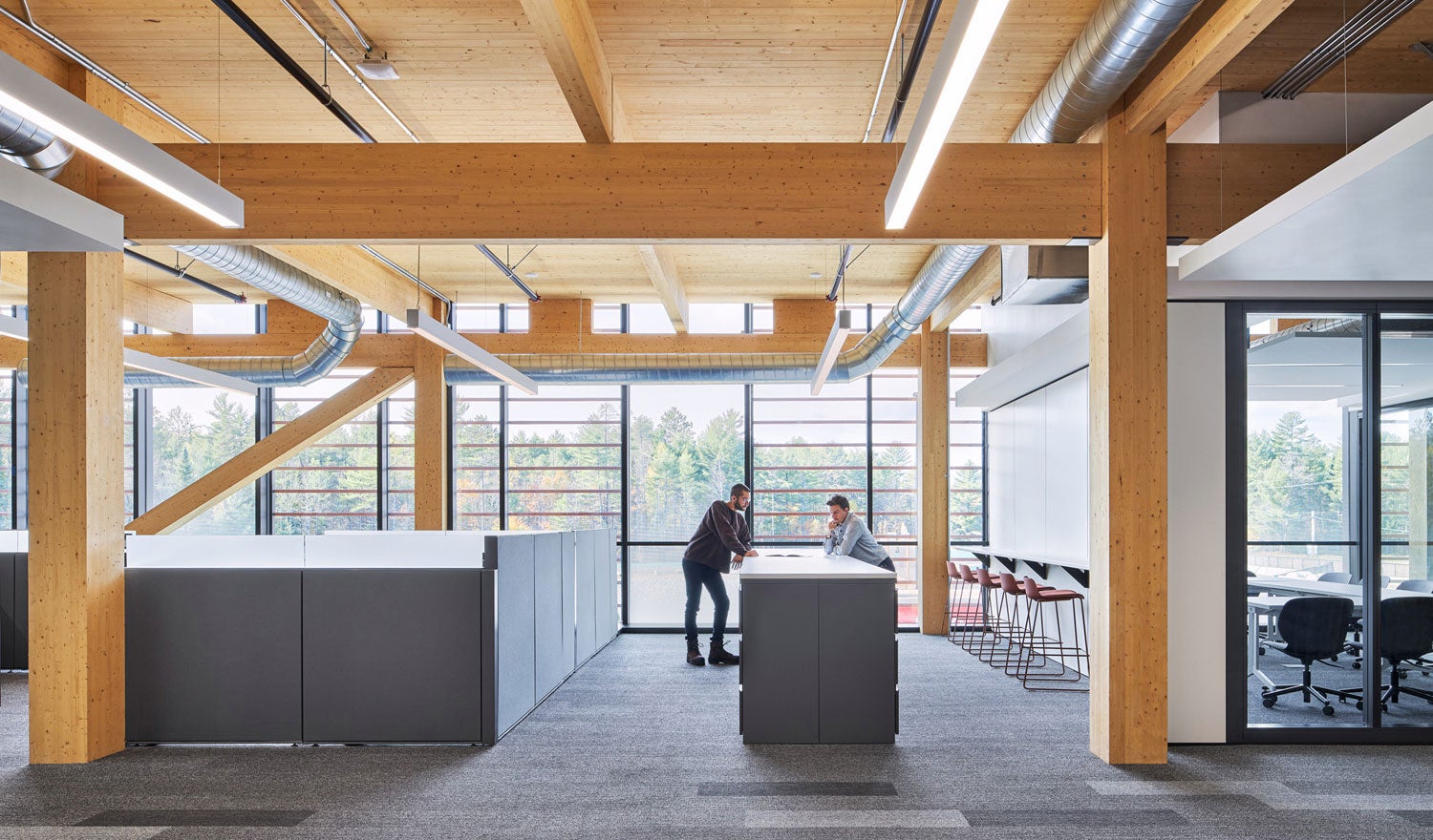 Two employees talking in an office space with wood interiors