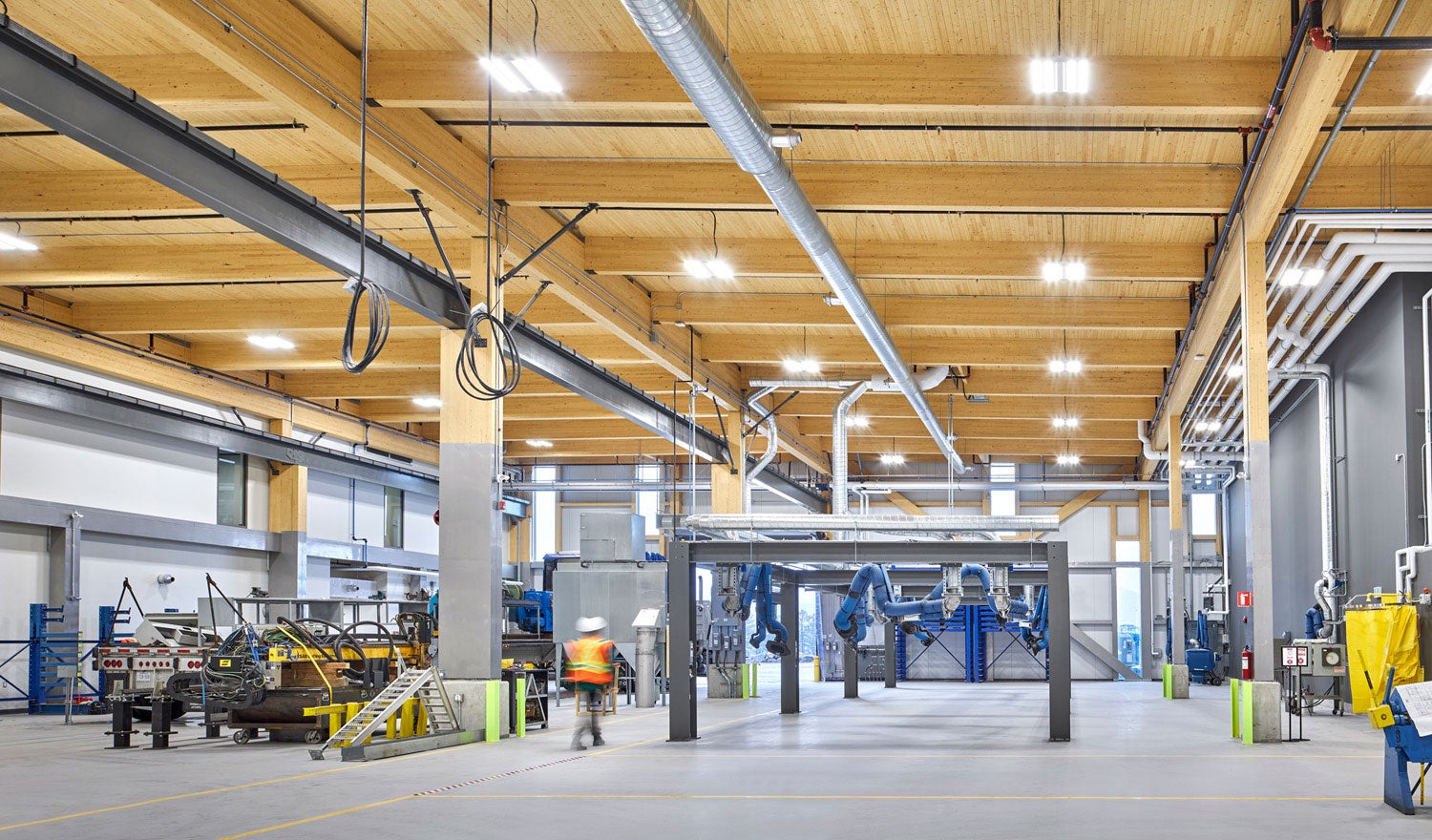 Person in construction apparel walking through a warehouse with wood interiors