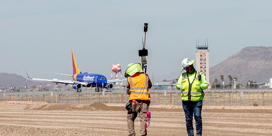 workers digitally measuring during construction of a runway at Tucson airport