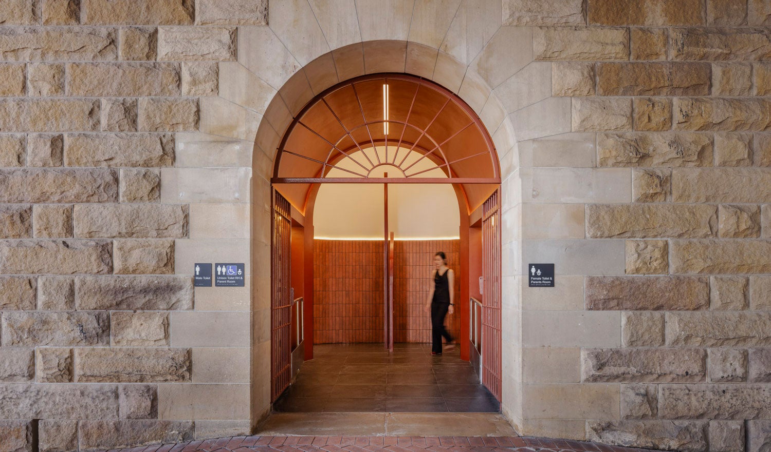Modern bathroom entrance with bronze interior palette and a person exiting