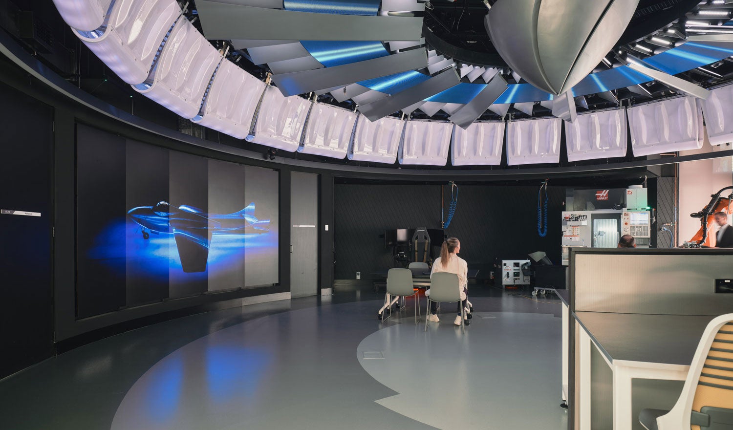 A modern university newsroom with an installation in the ceiling and purple lighting