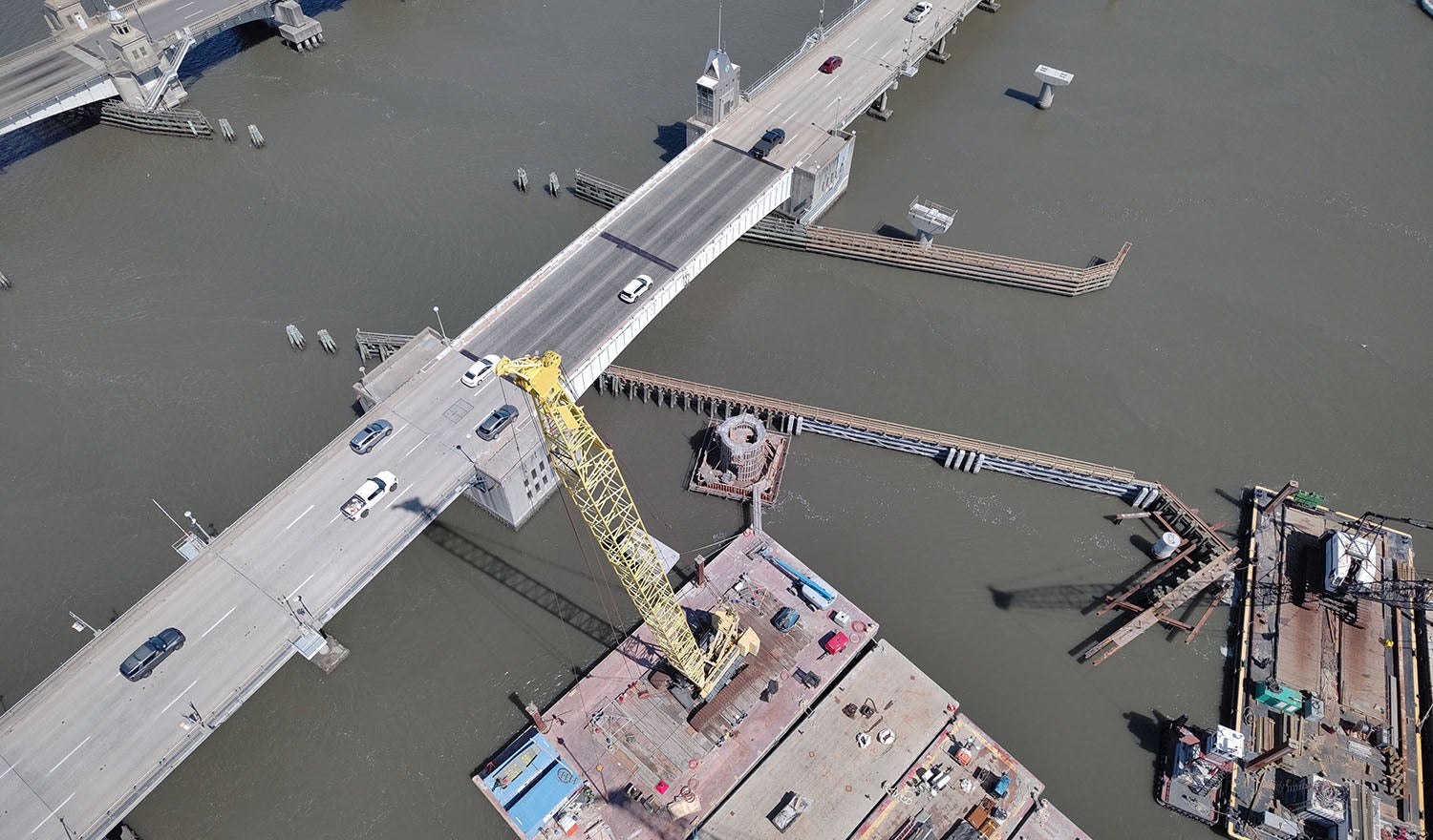 construction equipment in water near vehicle bridge