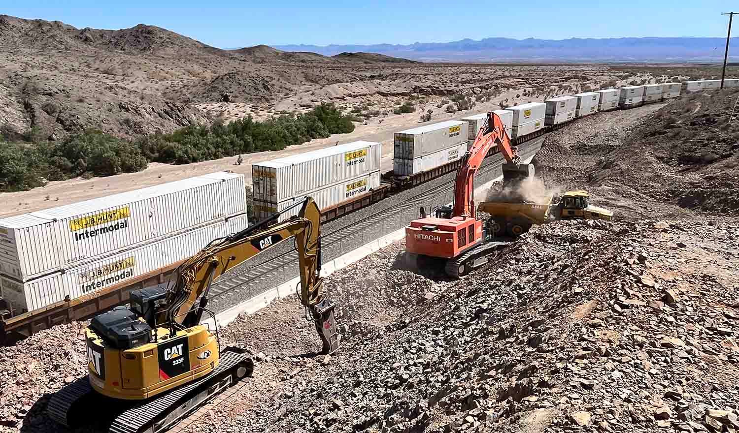 train passing construction equipment in desert