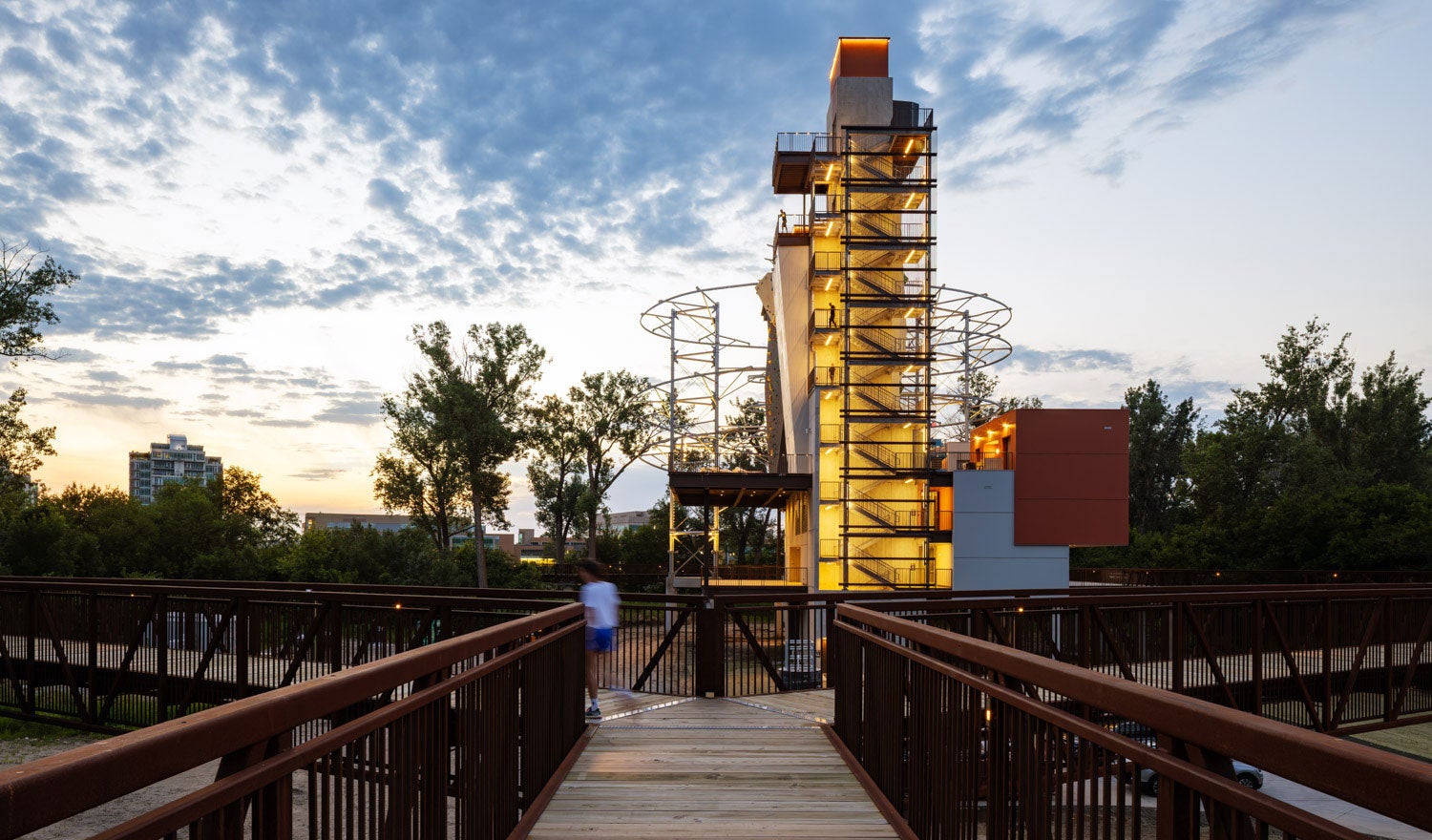 An adventure tower next to a boardwalk with lights shining from within